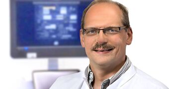 Porträtfoto Stefan Klingebiel Facharzt Neurologie vor Monitor