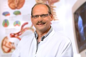 Porträtfoto Stefan Klingebiel Facharzt Neurologie vor Poster